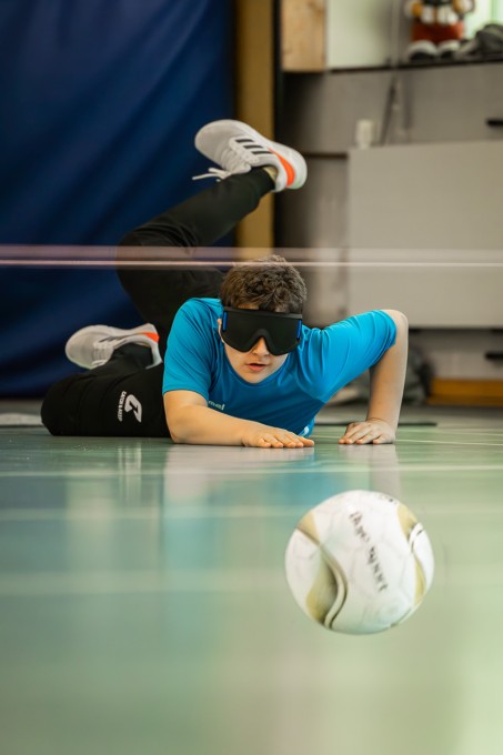 Ein Schüler liegt auf dem Boden und wirft einen Ball auf das gegnerische Tor.