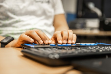 Hände liegen auf einer Braillezeile