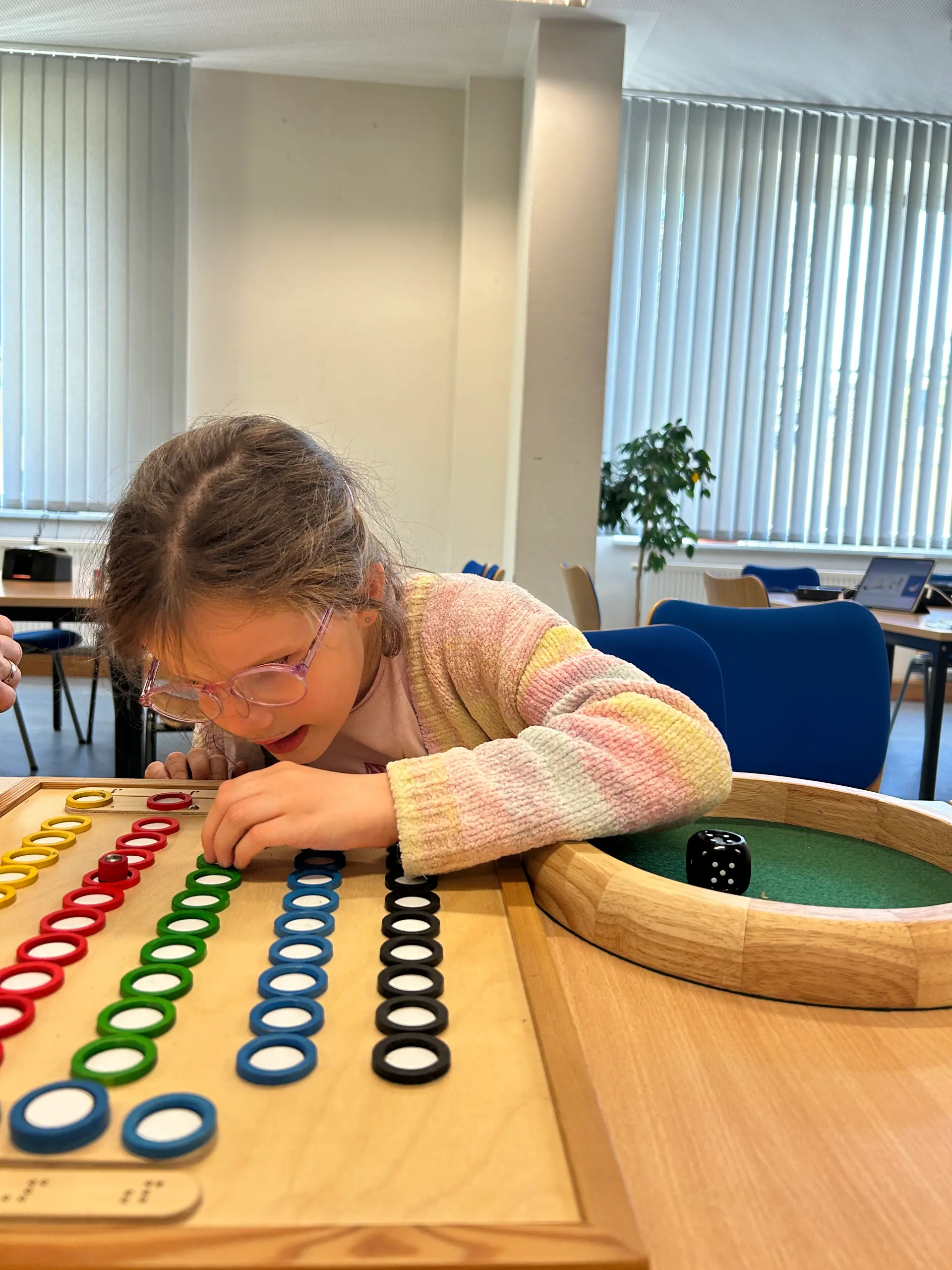 Eine Schülerin würfelt und setzt ihre Figur im Spiel „Wettrennen“