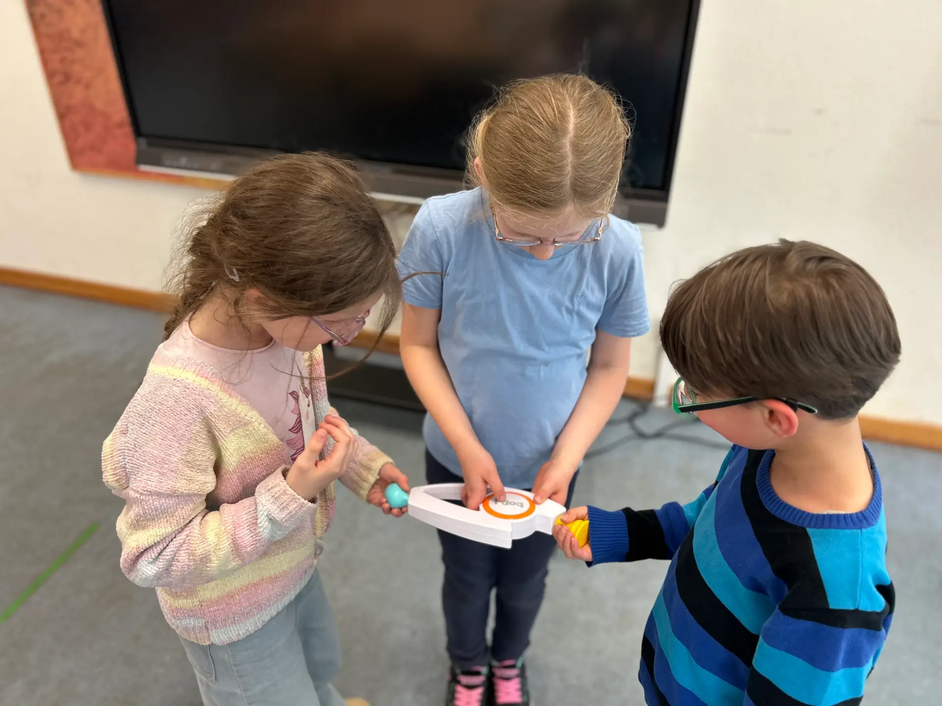 Drei Schüler*innen spielen gemeinsam das Reaktionsspiel „Bop It“