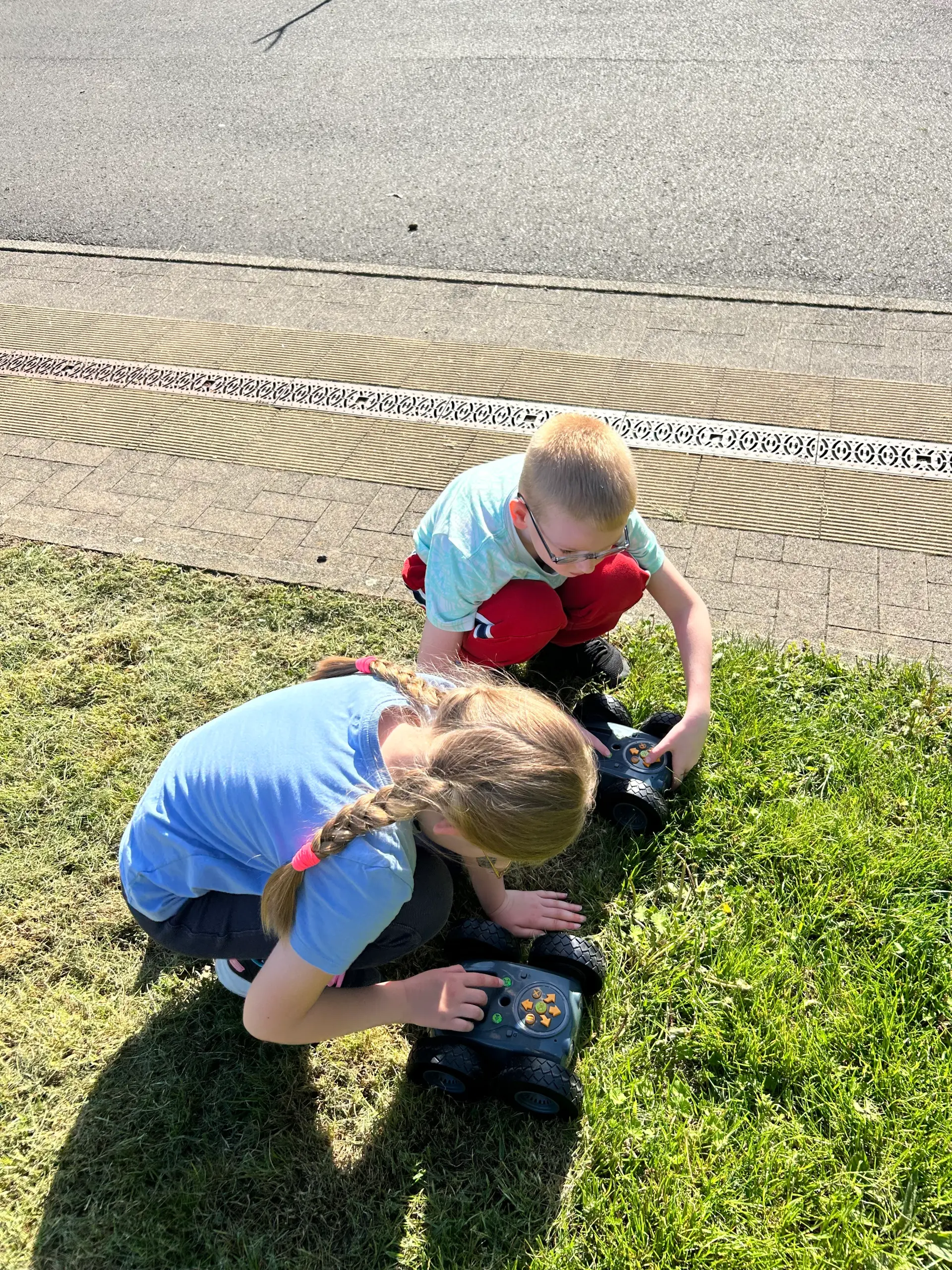 Zwei Schüler*innen lassen die Rugged Robots draußen auf der Wiese fahren