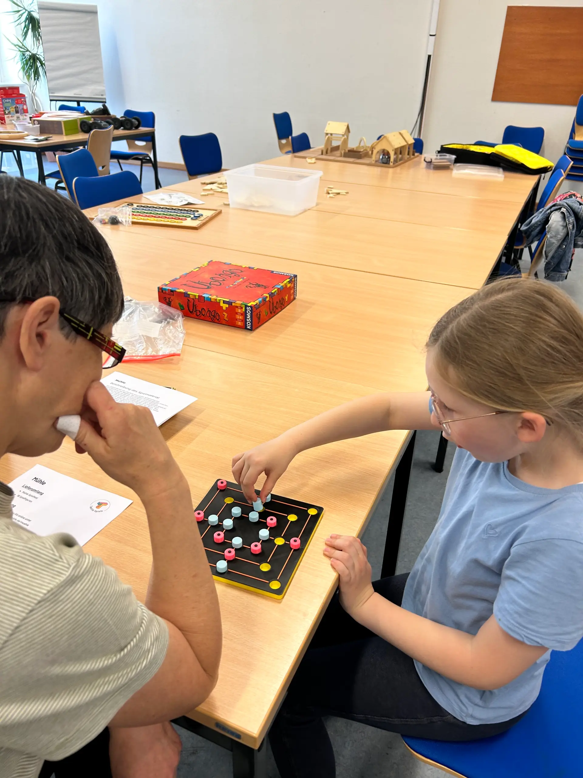 Eine Schülerin und eine Lehrerin spielen gemeinsam das Spiel „Mühle“