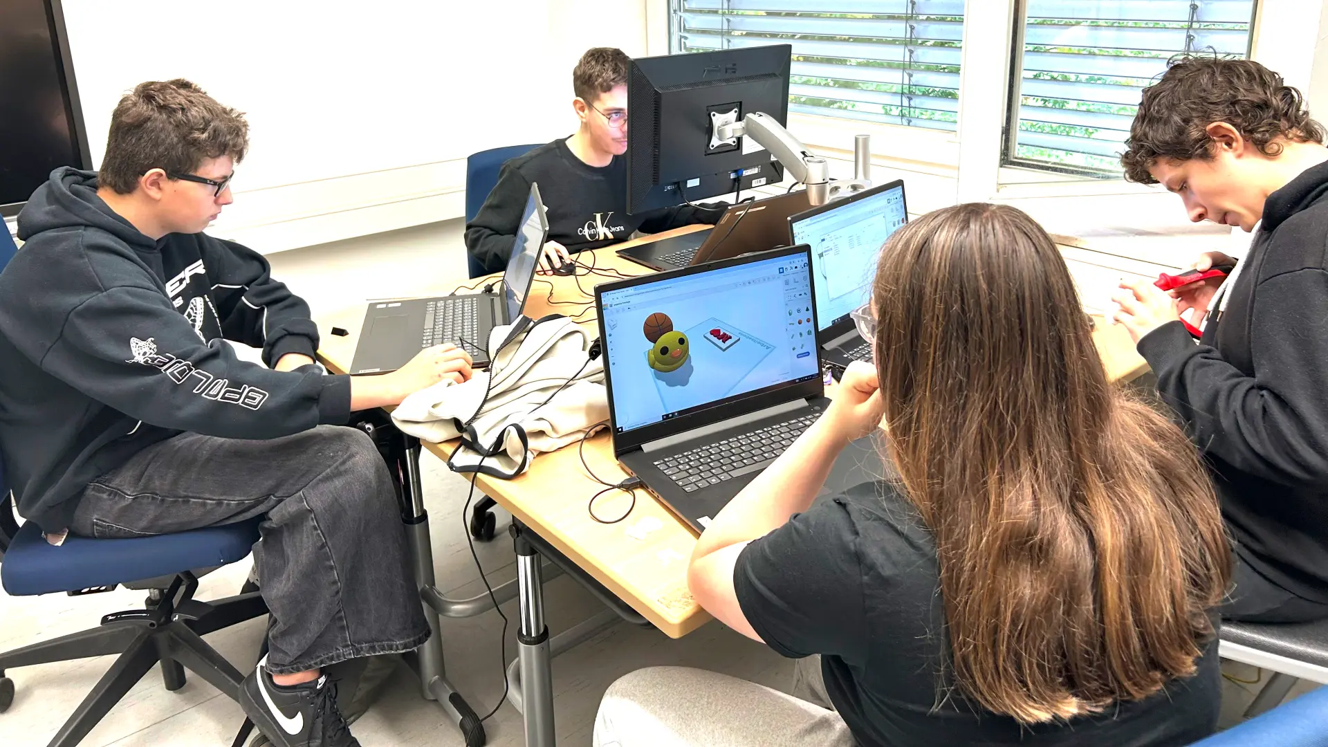 Vier Schüler*innen sitzen am PC und arbeiten.