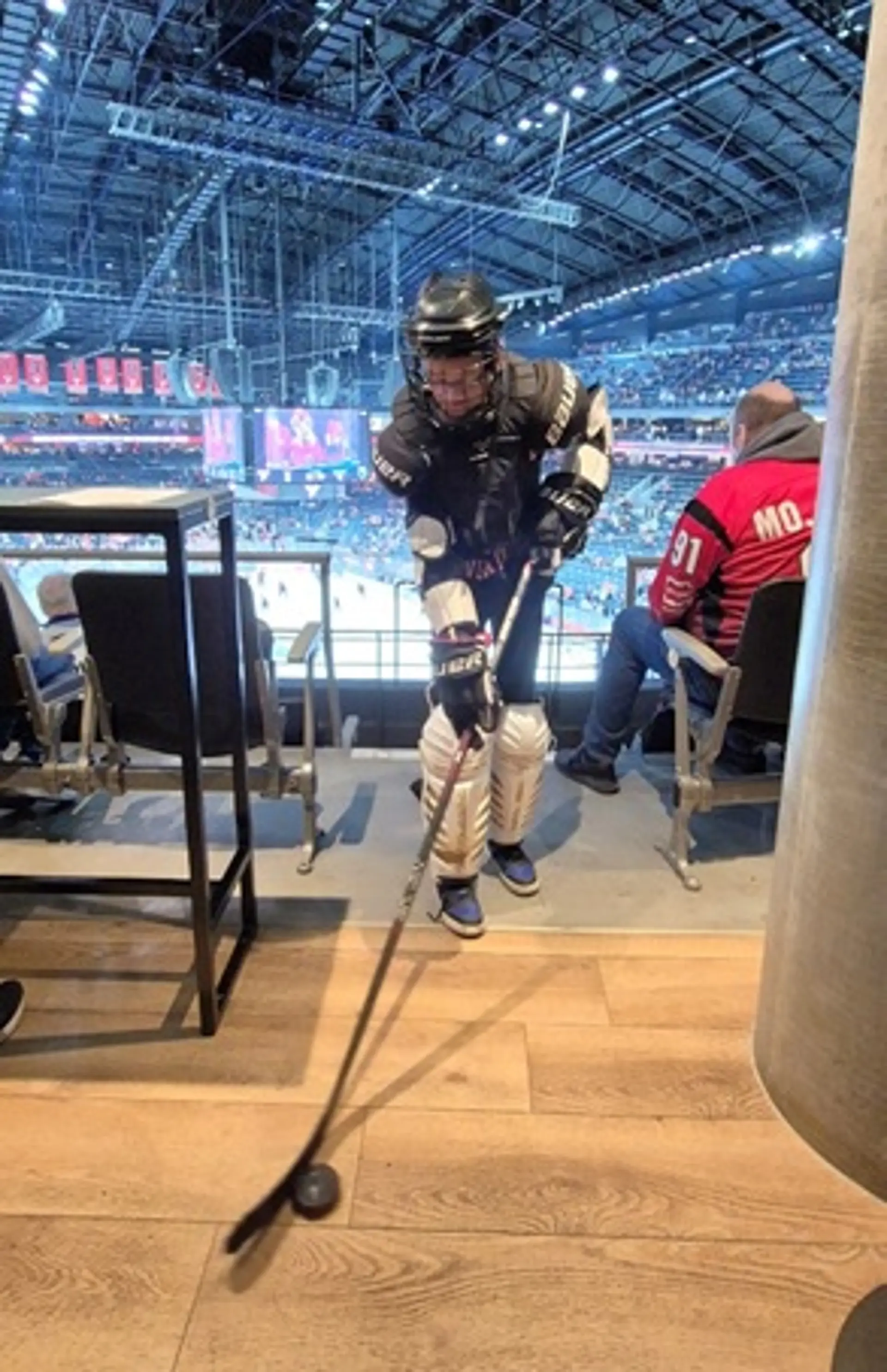 Ein Schüler in Eishockeymontur mit Schläger und Puck.