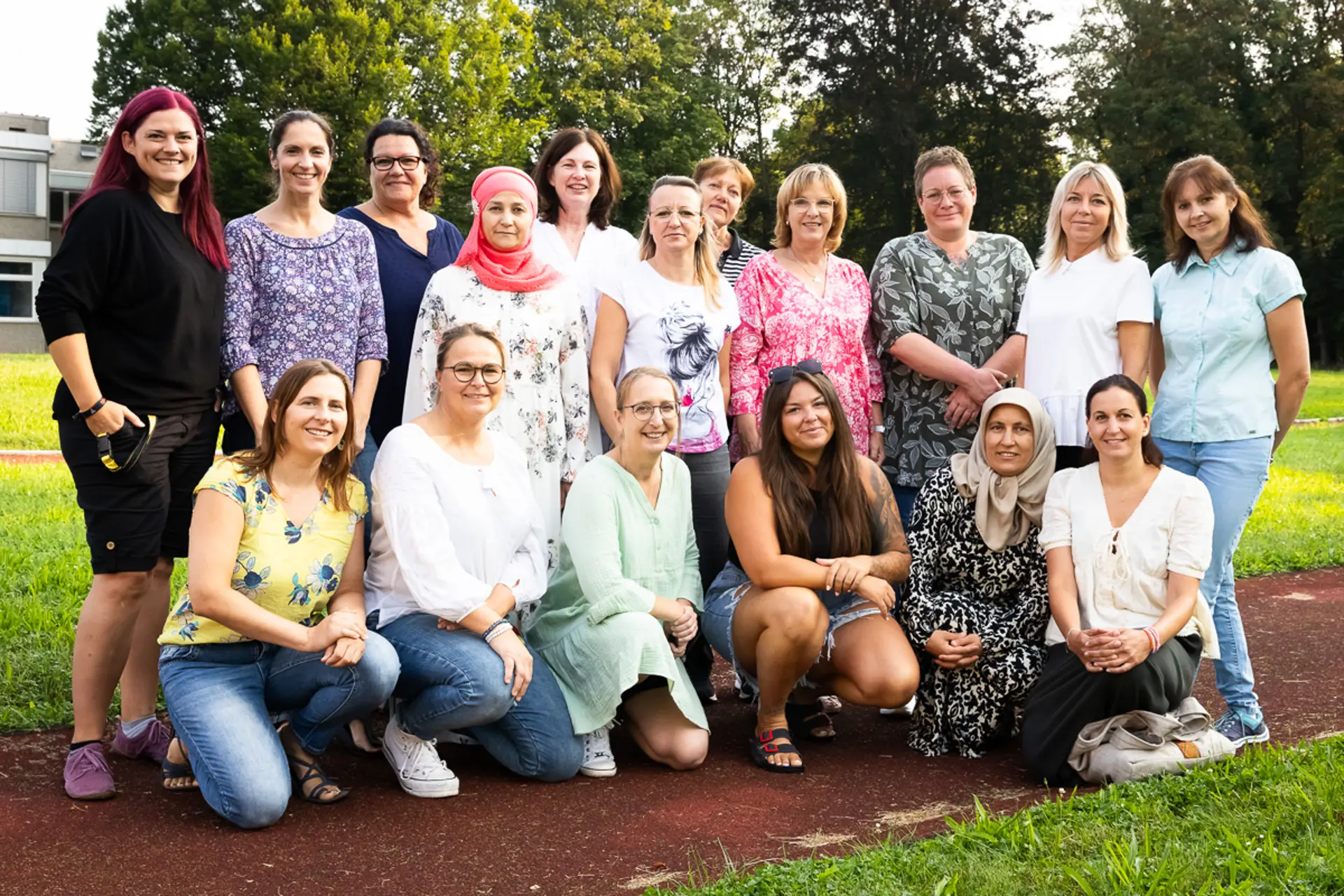 Porträtfoto von insgesamt 17 Pflegekräften im schulischen Außenbereich 
