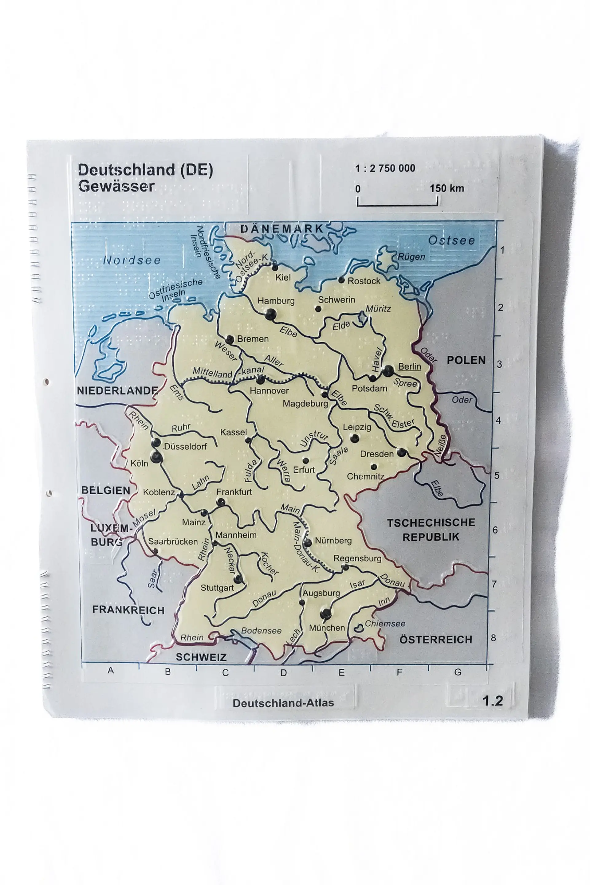 Eine taktile Karte von Deutschlands Gewässern. Die Grenzen zu den benachbarten Ländern sind in Rot und dicker markiert, die großen Flüsse sind in Blau markiert. Die Hauptstädte der einzelnen Bundesländer sind mit einem dicken Punkt gekennzeichnet. 