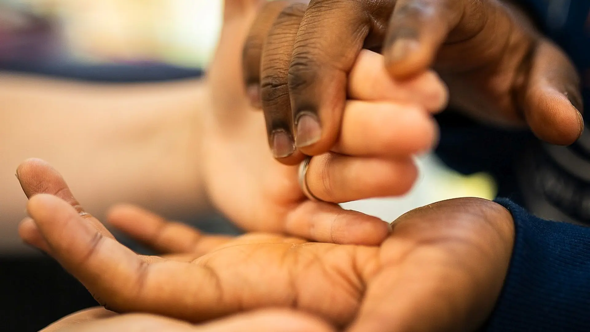 Die Hände von zwei Personen berühren sich, nur die Finger und die Hände sind zu sehen.